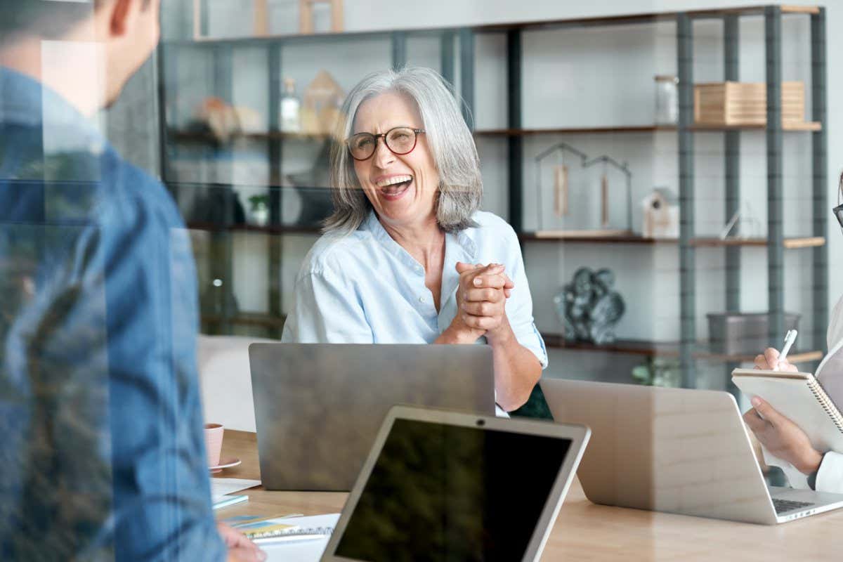 Happy mature old female mentor coach supervisor training young interns at group office meeting professional workshop. Cheerful middle aged teacher professor laughing with students at university class.; Shutterstock ID 1819892279; purchase_order: -; job: -; client: -; other: -