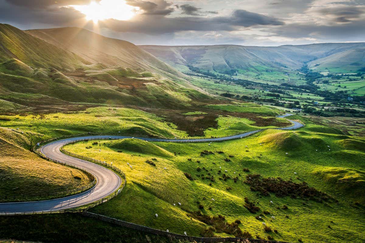 Sunset at Mam Tor, Peak District National Park, with a view along the winding road among the green hills down to Hope Valley, in Derbyshire, England.; Shutterstock ID 719075554; purchase_order: -; job: -; client: -; other: -
