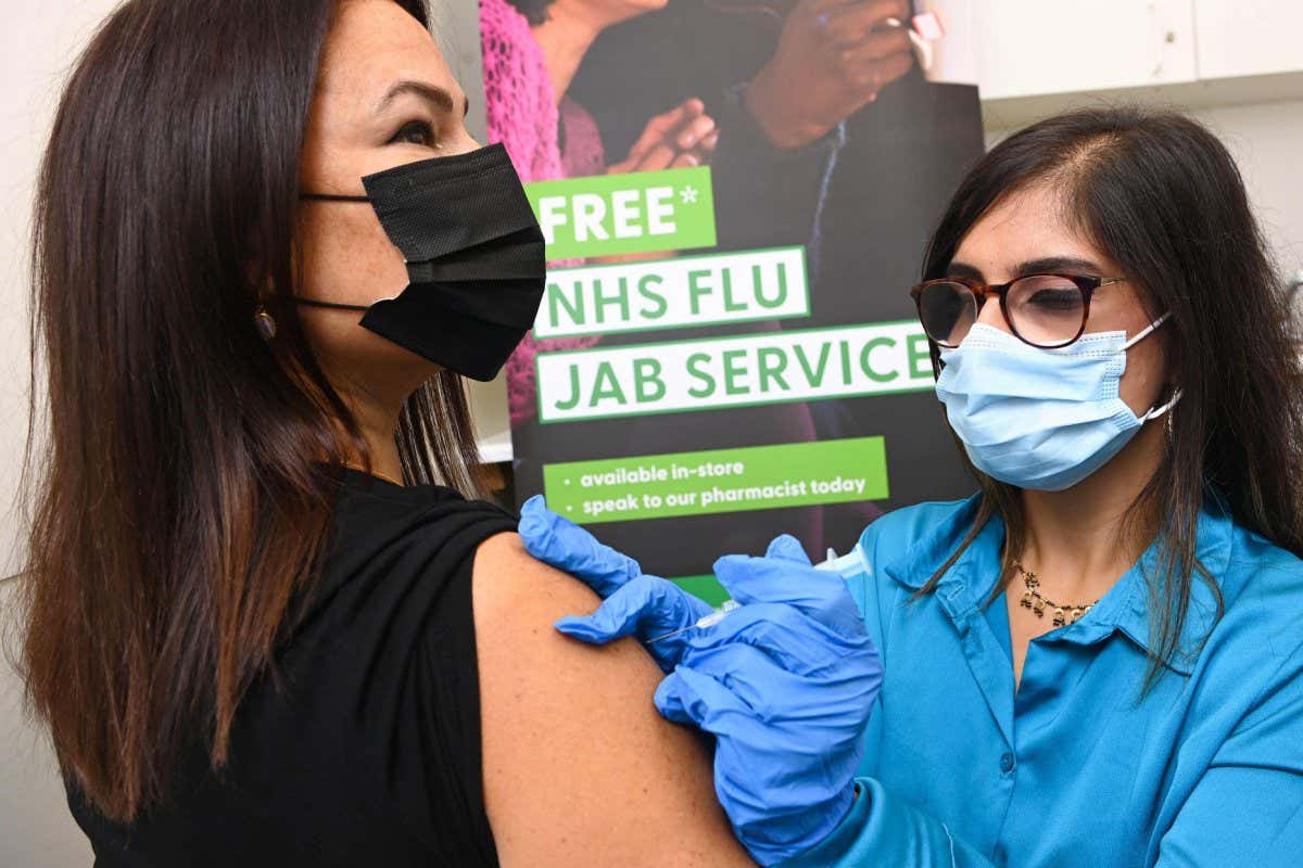A pharmacist administers a flu vaccine ahead of the UK's 2022/23 flu season
