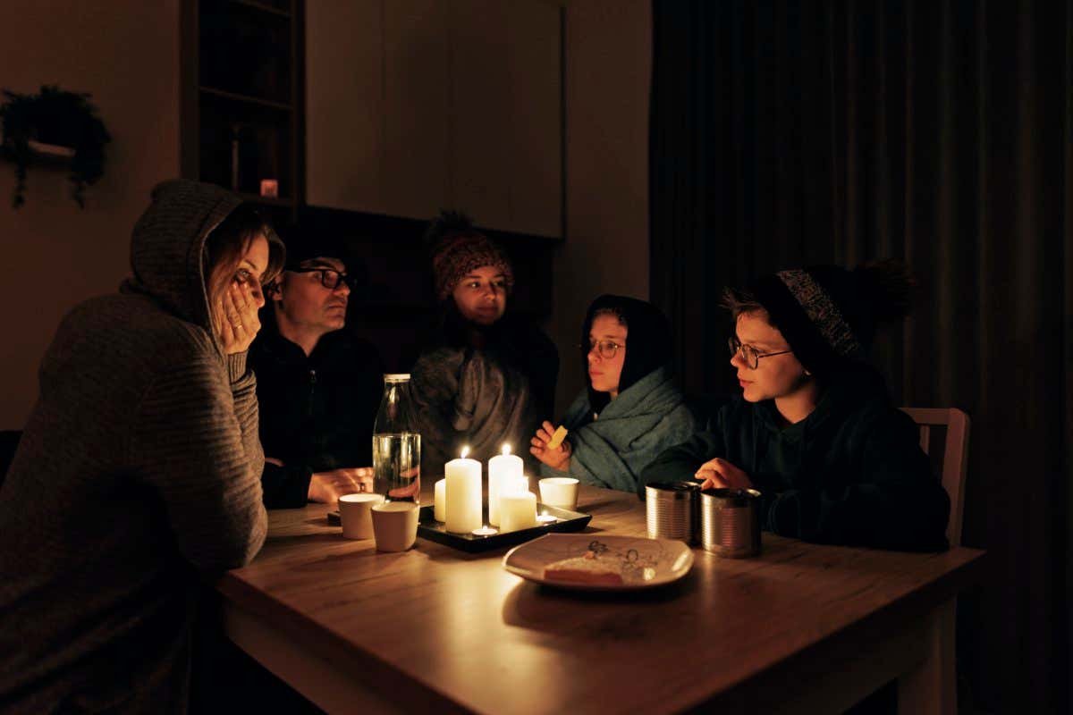 Family sits around a table by candlelight