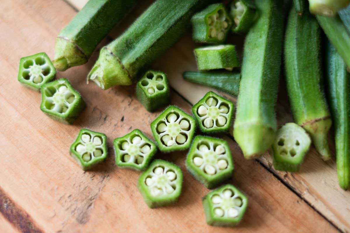 Okra partly sliced up on a chopping board