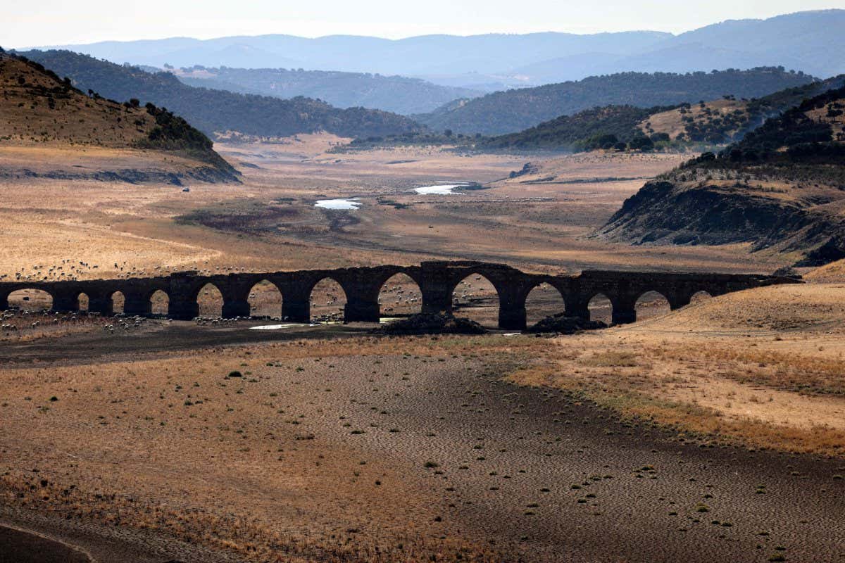 Part of the Guadiana river has dried up and gives way to dry land under the Puente de la Mesta medieval bridge in Villarta de los Montes, in the central-western Spanish region of Extremadura, on August 16, 2022. - Temperatures in Spain have been very high this summer with several unusual heat waves. Scientists say human-induced climate change is making extreme weather events including heatwaves and droughts more frequent and more intense. (Photo by THOMAS COEX / AFP) (Photo by THOMAS COEX/AFP via Getty Images)
