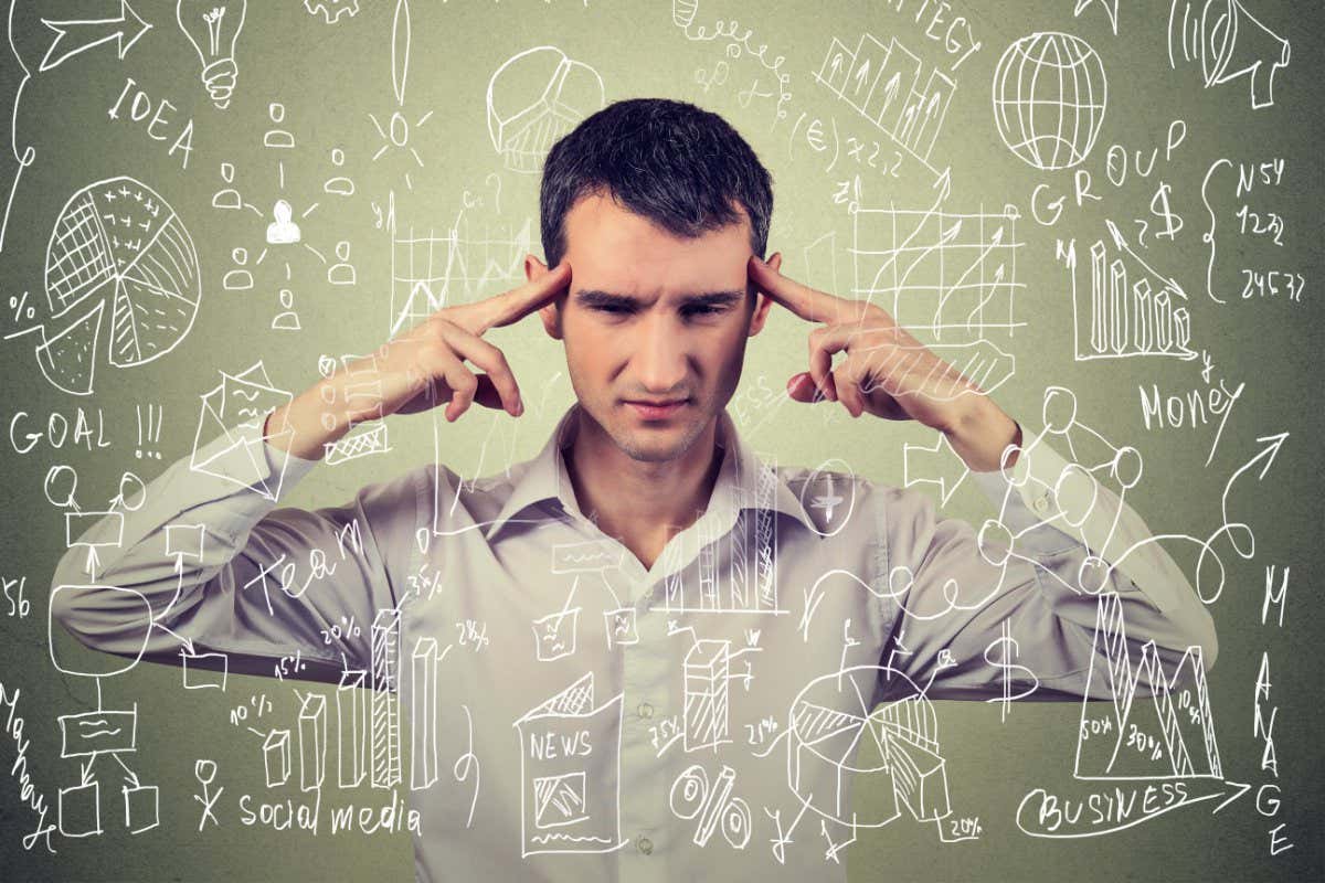 KE1WMA Young business man thinking hard how to manage difficult new project isolated on gray wall background. Life work balance concept.