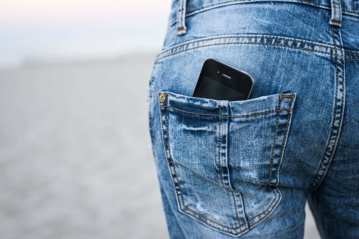 Closeup on smartphone in the back pocket of a womans jeans, blank screen with clipping path for you to add your own message or design. On the background of the beach and the sea; Shutterstock ID 453083140; purchase_order: -; job: -; client: -; other: -