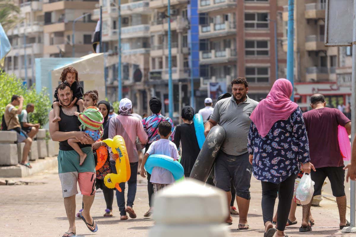 Egyptian families walk in the streets of Alexandria on their way to a beach in Alexandria amid a heatwave