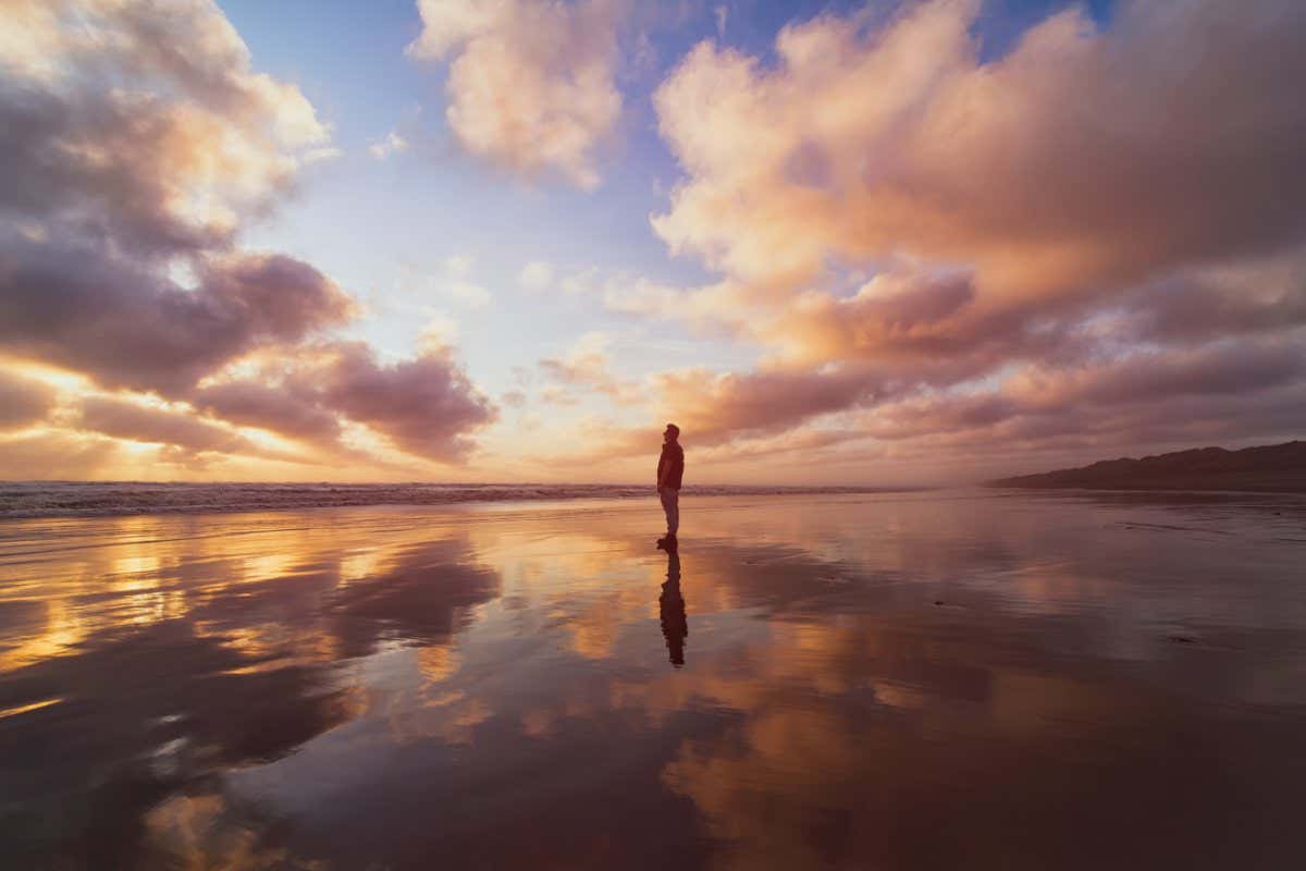 A man enjoying a beautiful sunset at Muriwai Beach, Auckland, New Zealand.