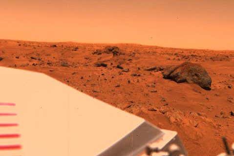 Original Caption Released with Image: Near the Viking 1 Lander on the Chryse Plains of Mars, 'Big Joe' stands a silent vigil. This large, often-photographed dark rock has a topping of reddish fine-grained silt that spills down its sides. It is about 2 meters (6.6 feet) long and lies about 8 meters (26 feet) from the spacecraft. The rough texture of the sides shows it to be coarse grained. Big Joe appears to be part of a field of large blocks that has a roughly circular alignment and which may be part of the rim of an ancient degraded crater. Some of the other blocks of the field can be seen to the left, extending out toward the horizon, perhaps 1.5 kilometers (1 mile) away. Drifts of fine-grained material cover the surface to the right and left of Big Joe. The part of the Lander that is visible in the lower left is the cover of the nuclear power supply. Image Credit: NASA/JPL