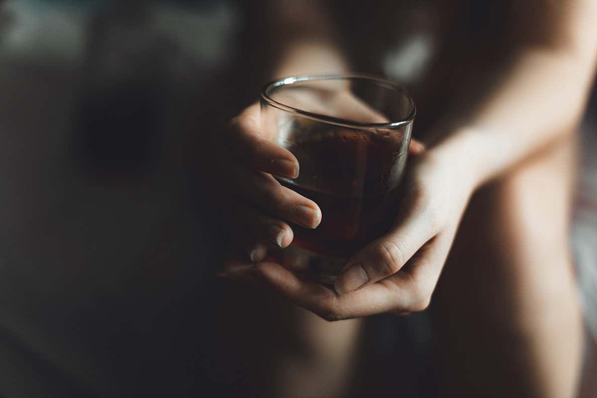 A person holding a glass of alcohol