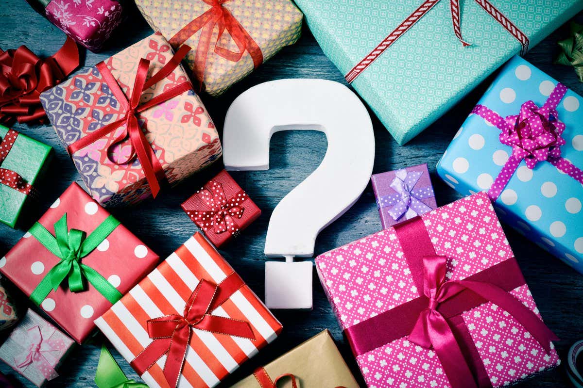 HDY64X high-angle shot of many gifts wrapped in nice papers and tied with ribbons of different colors and a white three-dimensional question tag in the cente