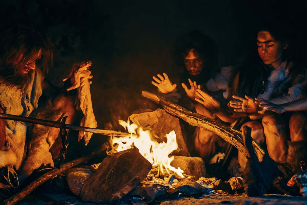 Neanderthal or Homo Sapiens Family Cooking Animal Meat over Bonfire and then Eating it. Tribe of Prehistoric Hunter-Gatherers Wearing Animal Skins Eating in a Dark Scary Cave at Night; Shutterstock ID 1595983549; purchase_order: -; job: -; client: -; other: -