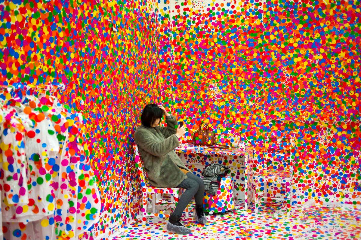 February 11, 2014 - Shanghai, China: A young woman takes a 'selfie' while sitting on a chair inside Japanese artist Yayoi Kusama's 'Obliteration Room': an installation of a white room increasingly covered by museum attendees with colored dots. Yayoi Kusama's 'A Dream I Dreamed' is her first touring exhibition in Asia. The show's only Chinese appearance is at Shanghai's Museum of Contemporary Art. (Dave Tacon/Polaris) /// Credit: Dave Tacon / Polaris / eyevine Please agree fees before use. SPECIAL RATES MAY APPLY. For further information please contact eyevine tel: +44 (0) 20 8709 8709 e-mail: info@eyevine.com www.eyevine.com
