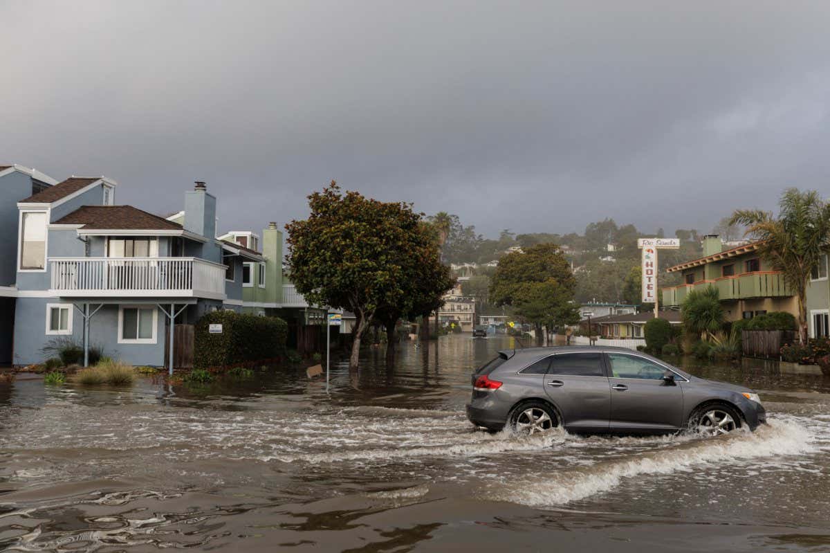 A vehicle travels along a flooded street after 