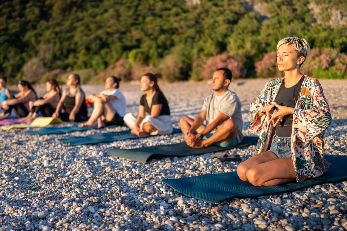 small group of people meditating on the beach. doing yoga when the sun rising.