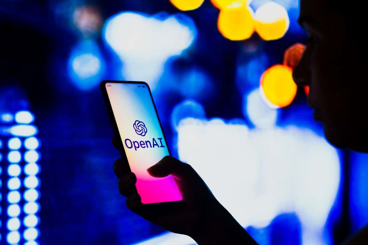 A hand holds a smartphone with the OpenAI logo
