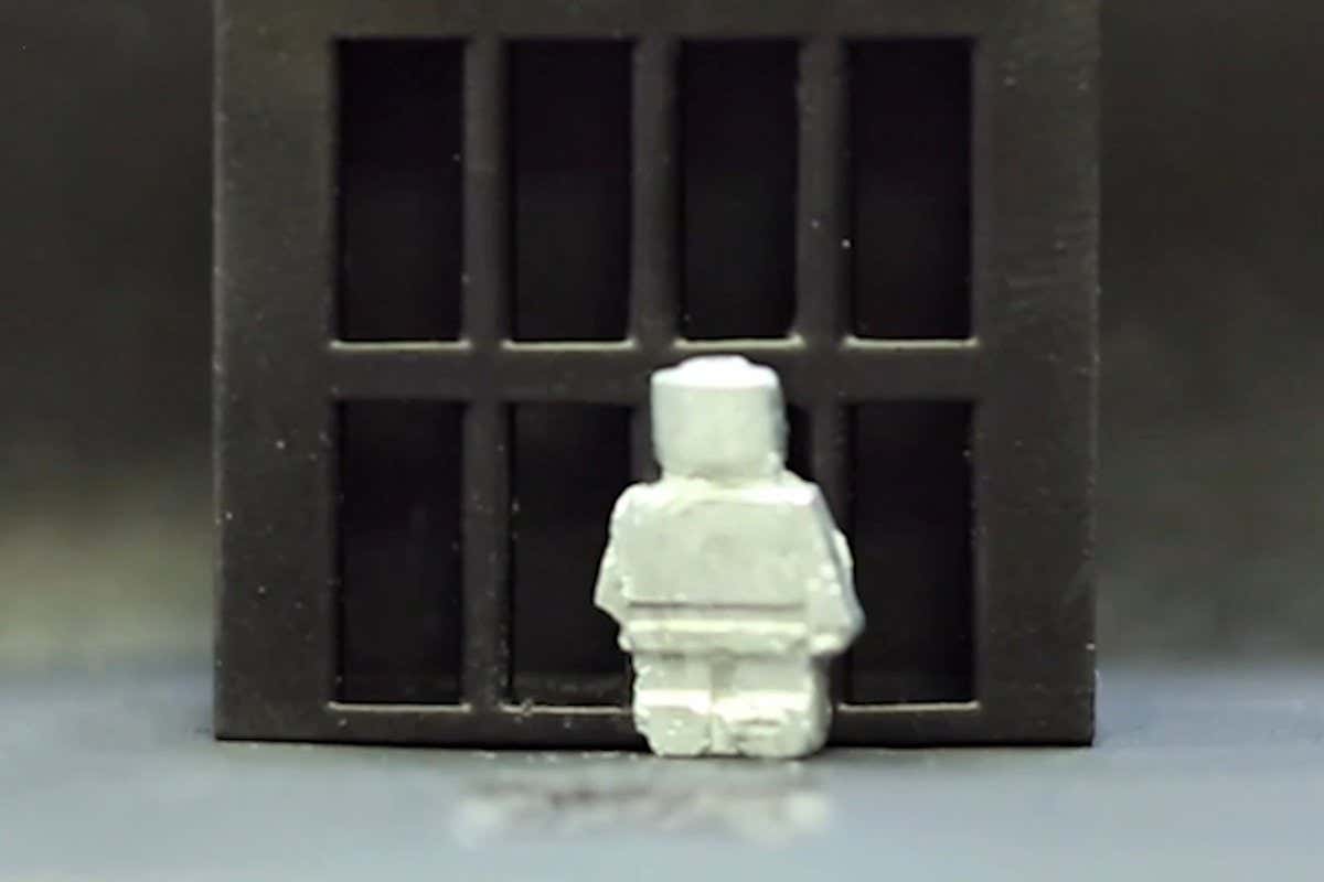 A white robot shaped like a person stands in front of the bars of a cage, preparing to start the process of liquifying to escape by flowing through the bars.