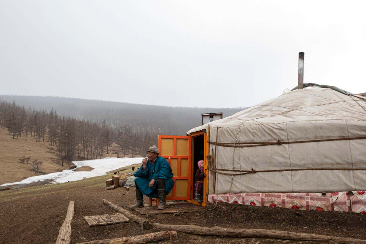 Mongolia - Uvurkhangai province - Bukhuu???s 70 year old father Davaasuren Tsogt sitting right outside his ger, smocking a traditional hand rolled cigarette.