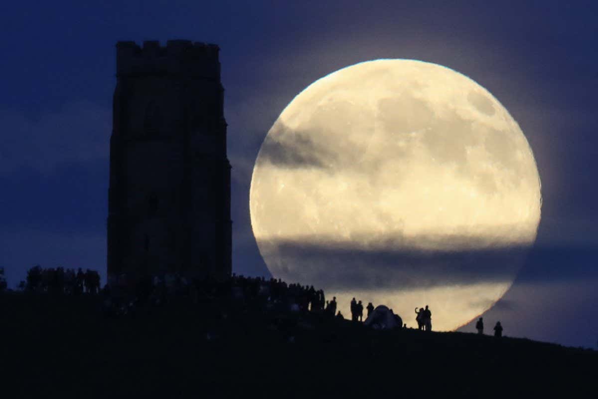 GLASTONBURY, ENGLAND - JUNE 20: A full moon rises behind Glastonbury Tor as people gather to celebrate the summer solstice on June 20, 2016 in Somerset, England. Tonight's strawberry moon, a name given to the full moon in June by Native Americans because it marks the beginning of strawberry picking season, last occurred on the solstice on June 22, 1967 and it will not happen again on the summer solstice for another 46 years until June 21, 2062. (Photo by Matt Cardy/Getty Images)