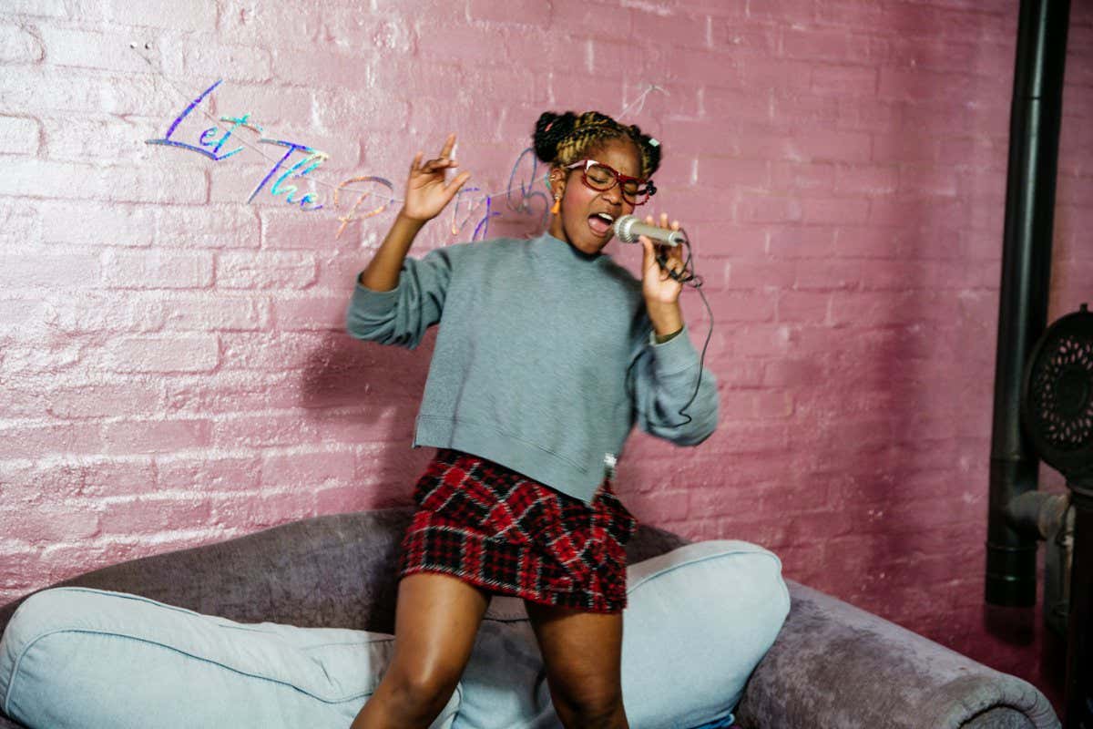 A woman singing while standing on a couch