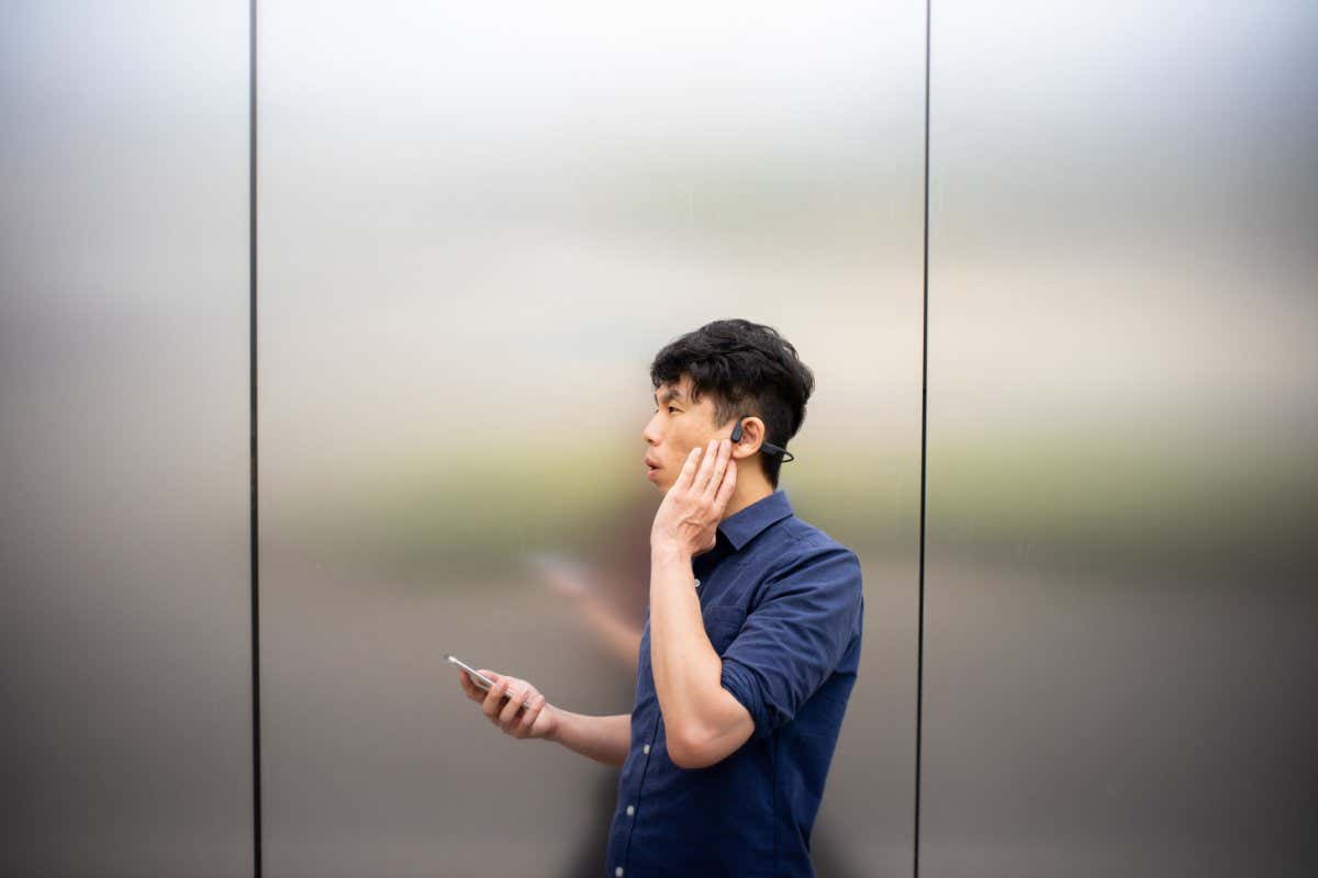 A man using bone-conduction earphones to make a phone call