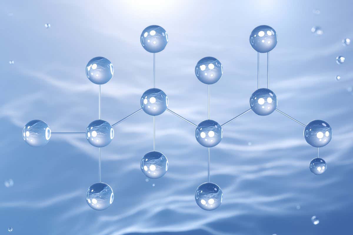 Against a shimmery gray background, roughly a dozen illustrated translucent balls and sticks are arranged in the formation of the 3D molecular structure of perfluorobutanoic acid