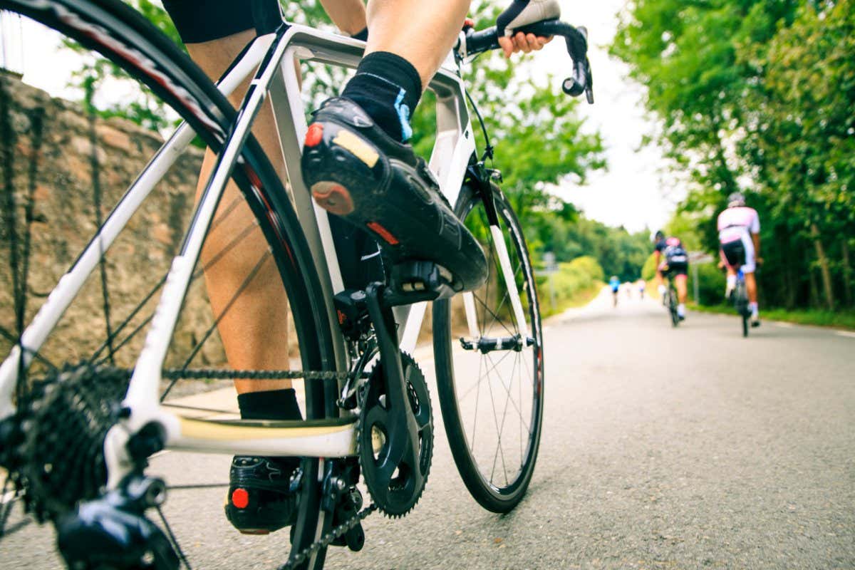 A low angle action shot of a road cyclist approaching a smooth tarmac hill on a group ride around Seva, Catalonia, Spain.