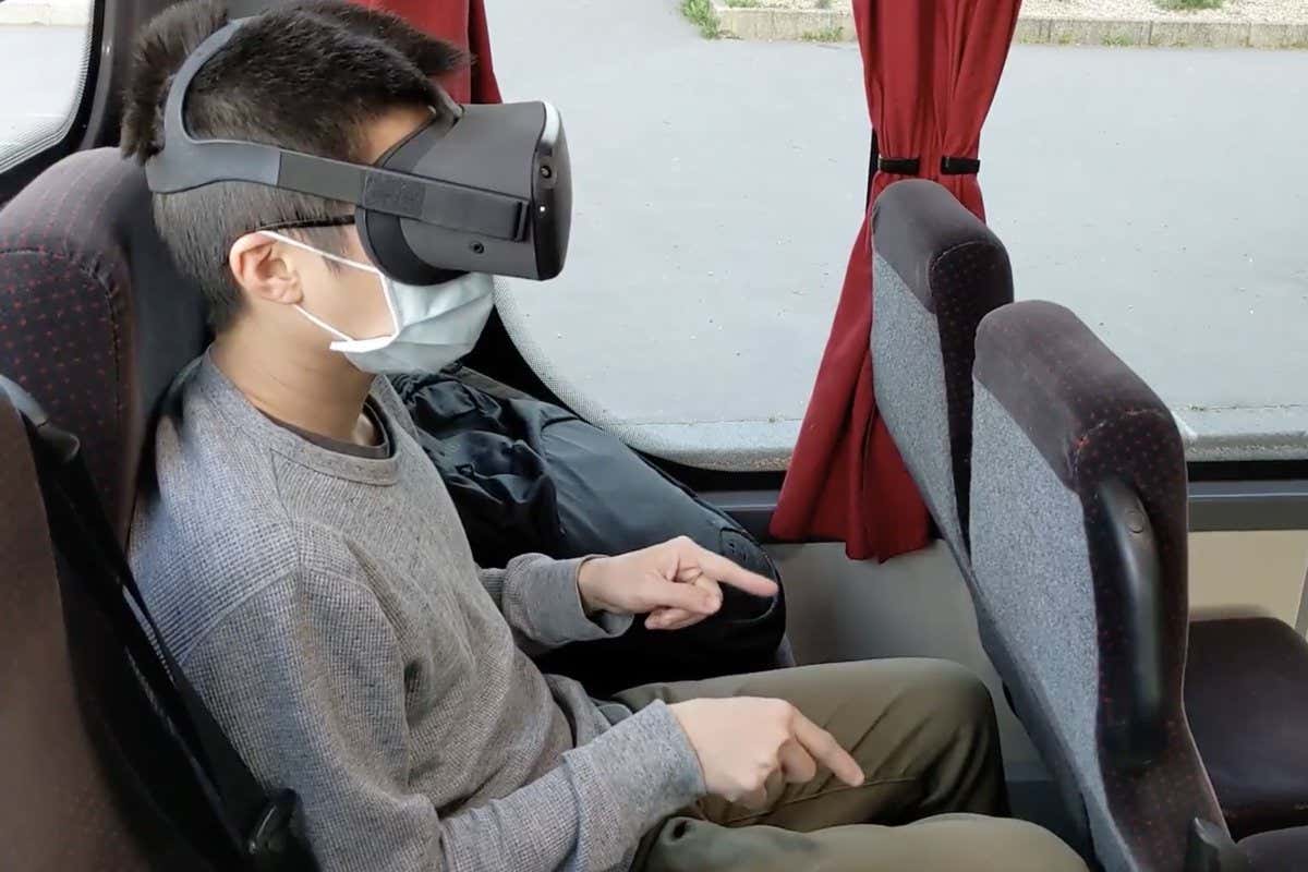 Person on a bus wearing a VR headset and moving their fingers