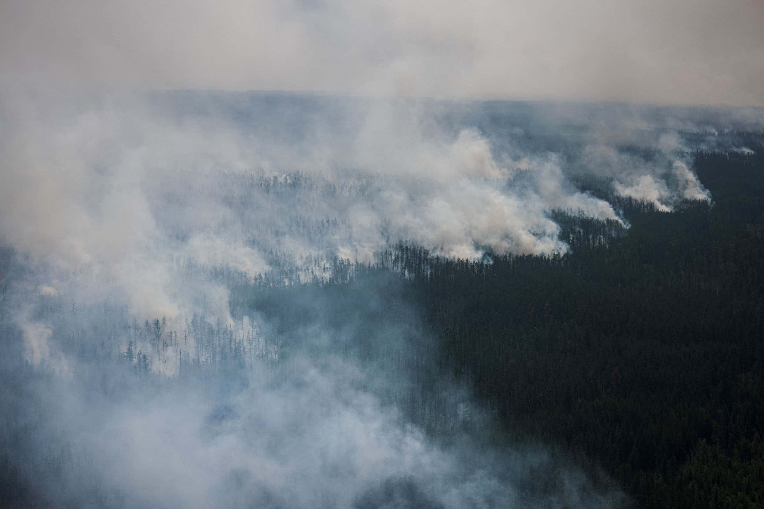 This aerial picture taken from an airplane on July 27, 2021, shows the smoke rising from a forest fire outside the village of Berdigestyakh, in the republic of Sakha, Siberia. - Russia is plagued by widespread forest fires, with the Sakha-Yakutia region in Siberia being the worst affected. According to many scientists, Russia -- especially its Siberian and Arctic regions -- is among the countries most exposed to climate change. The country has set numerous records in recent years and in June 2020 registered 38 degrees Celsius (100.4 degrees Fahrenheit) in the town of Verkhoyansk -- the highest temperature recorded above the Arctic circle since measurements began. (Photo by Dimitar DILKOFF / AFP) (Photo by DIMITAR DILKOFF/AFP via Getty Images)
