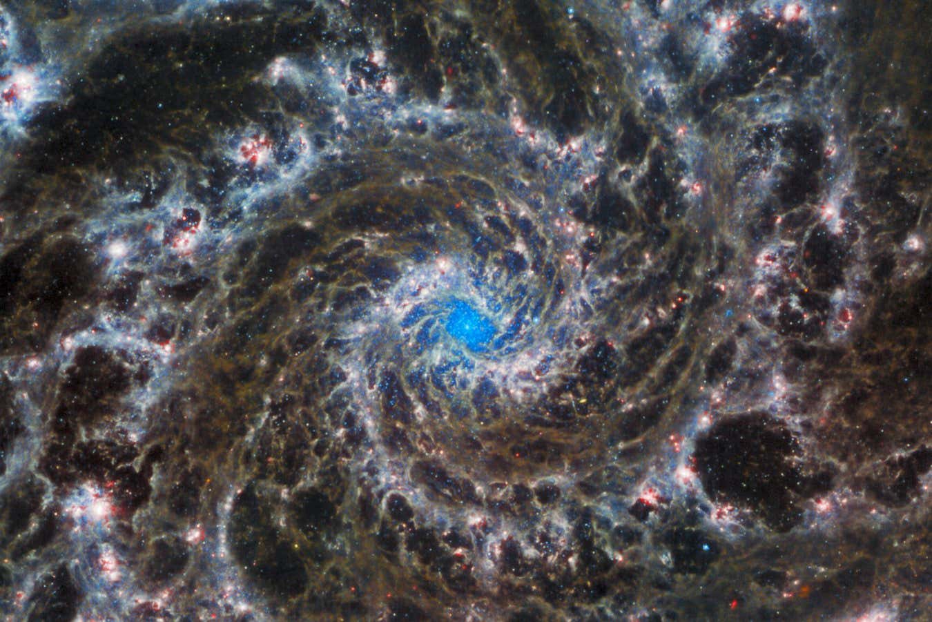 This image from the NASA/ESA/CSA James Webb Space Telescope shows the heart of M74, otherwise known as the Phantom Galaxy. Webb???s sharp vision has revealed delicate filaments of gas and dust in the grandiose spiral arms which wind outwards from the centre of this image. A lack of gas in the nuclear region also provides an unobscured view of the nuclear star cluster at the galaxy's centre. M74 is a particular class of spiral galaxy known as a ???grand design spiral???, meaning that its spiral arms are prominent and well-defined, unlike the patchy and ragged structure seen in some spiral galaxies. The Phantom Galaxy is around 32 million light-years away from Earth in the constellation Pisces, and lies almost face-on to Earth. This, coupled with its well-defined spiral arms, makes it a favourite target for astronomers studying the origin and structure of galactic spirals. Webb gazed into M74 with its Mid-InfraRed Instrument (MIRI) in order to learn more about the earliest phases of star formation in the local Universe. These observations are part of a larger effort to chart 19 nearby star-forming galaxies in the infrared??by the international PHANGS collaboration. Those galaxies have already been observed using the NASA/ESA Hubble Space Telescope and ground-based observatories. The addition of crystal-clear Webb observations at longer wavelengths will allow astronomers to pinpoint star-forming regions in the galaxies, accurately measure the masses and ages of star clusters, and gain insights into the nature of the small grains of dust drifting in interstellar space.Hubble observations of M74 have revealed particularly bright areas of star formation known as HII regions. Hubble???s sharp vision at ultraviolet and visible wavelengths complements Webb???s unparalleled sensitivity at infrared wavelengths, as do observations from ground-based radio telescopes such as the Atacama Large Millimeter/submillimeter Array, ALMA. By combining data from telescopes operating across the??electromagnetic spectrum, scientists can gain greater insight into astronomical objects than by using a single observatory ??? even one as powerful as Webb! MIRI was contributed by ESA and NASA, with the instrument designed and built by a consortium of nationally funded European Institutes (the MIRI European Consortium) in partnership with JPL and the University of Arizona. Links Pan of the Phantom Galaxy Hubble and Webb Showcase M74 Pan of Combined optical/mid-infrared image of M74 (Hubble and Webb) Image B Image C