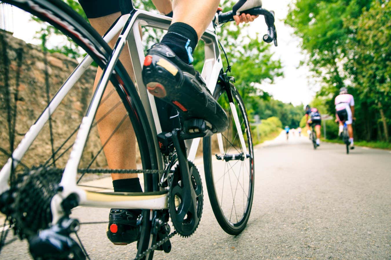 A low angle action shot of a road cyclist approaching a smooth tarmac hill on a group ride around Seva, Catalonia, Spain.