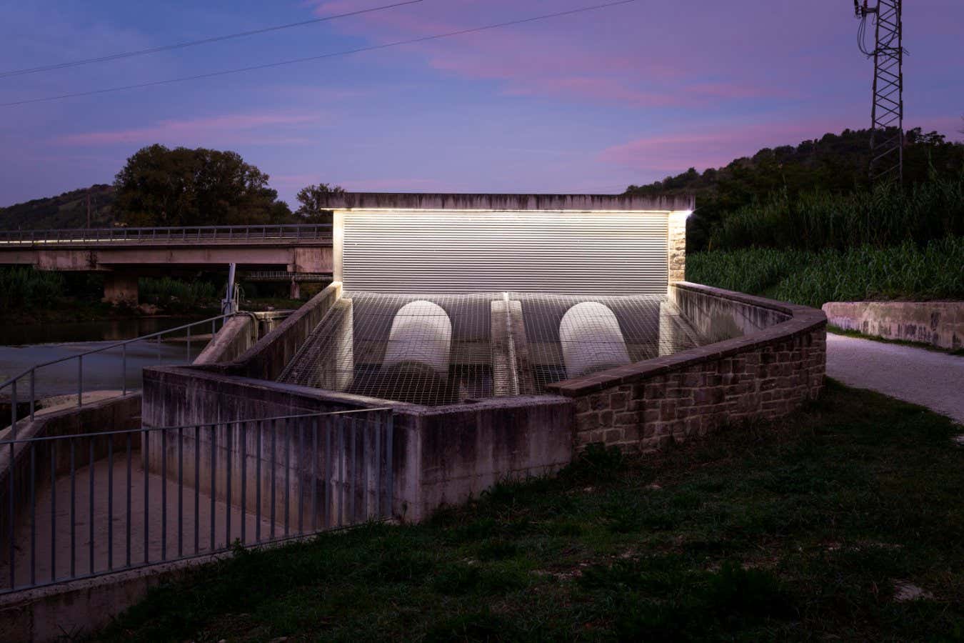 A hydroelectric plant on the Esino River at Angeli di Rosora, Ancona, Italy. Built in 2013, inside the building two hydraulic screws exploit the water current to produce electricity for the micro-grid of the 