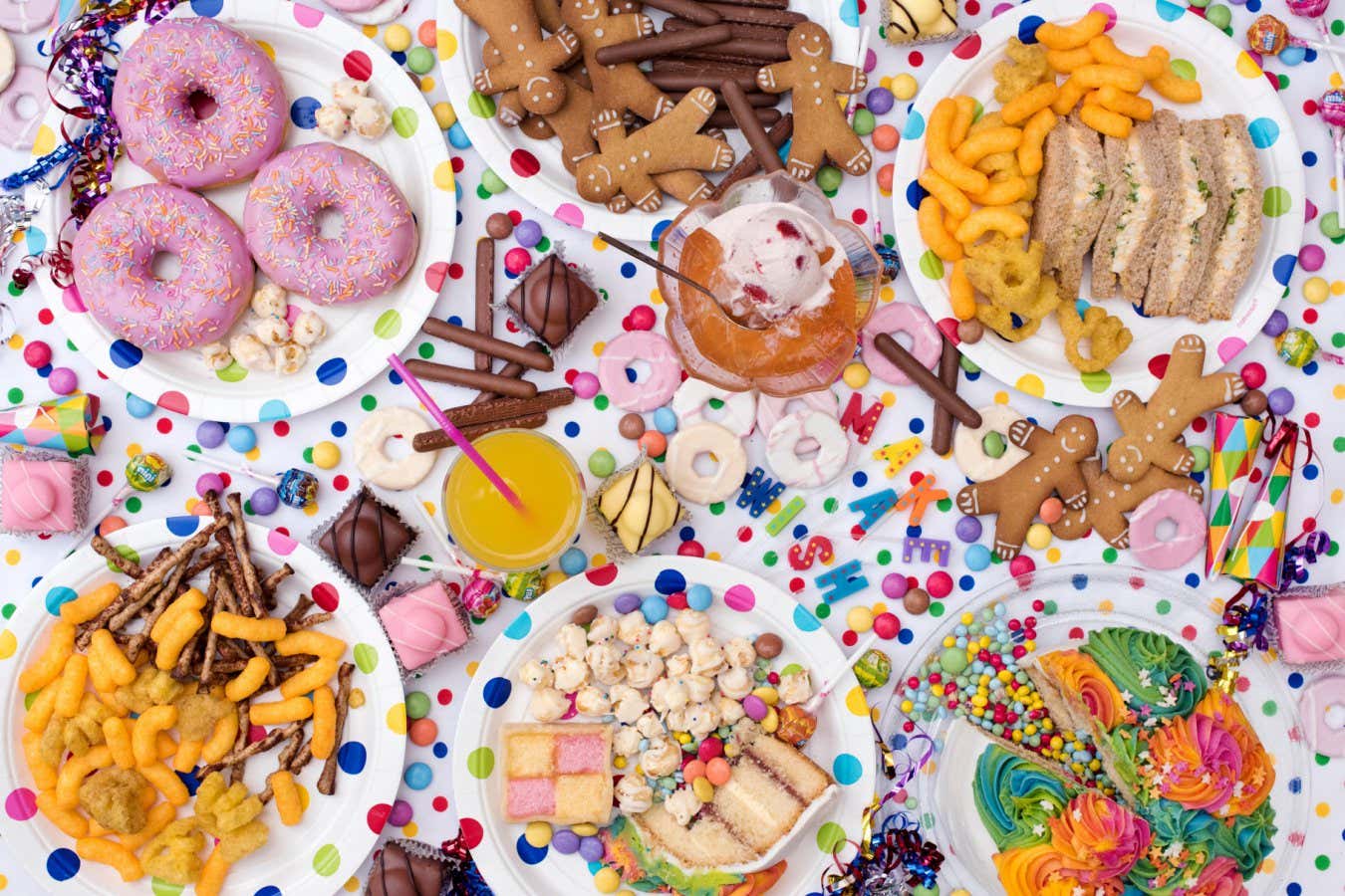 HT8R68 Childrens party food including sandwiches, cake, jelly and ice cream, biscuits, crisps, sweets and doughnuts on a polka dot background. Pattern