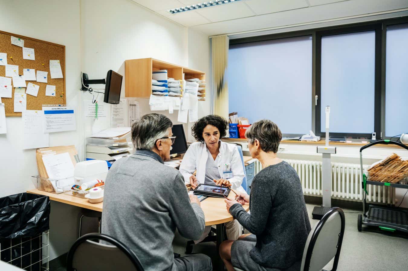 A clinical doctor talking to a couple of patients in her office at the hospital.