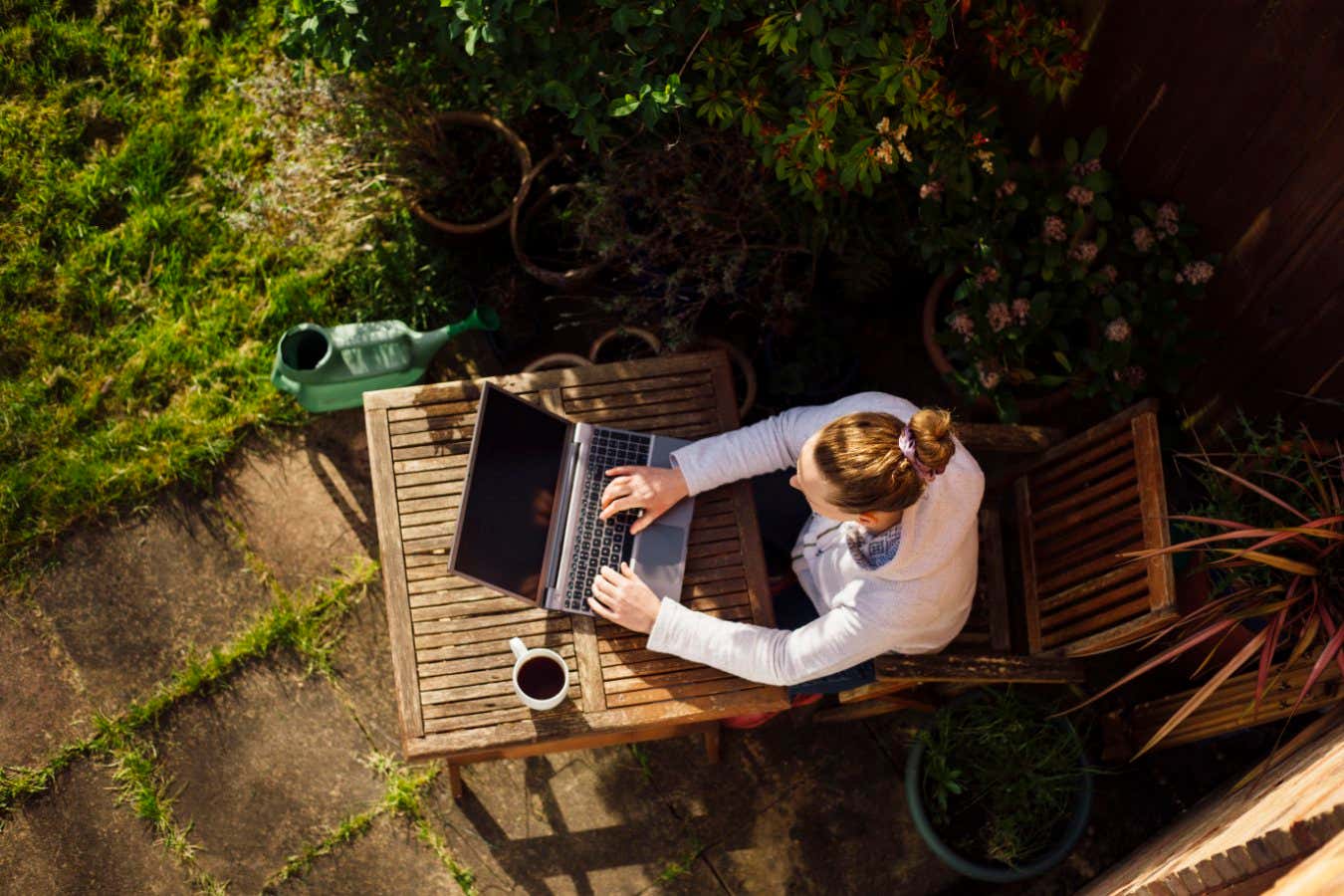 UK, Essex, Harlow, elevated view of a woman working from home in her garden using a laptop computer