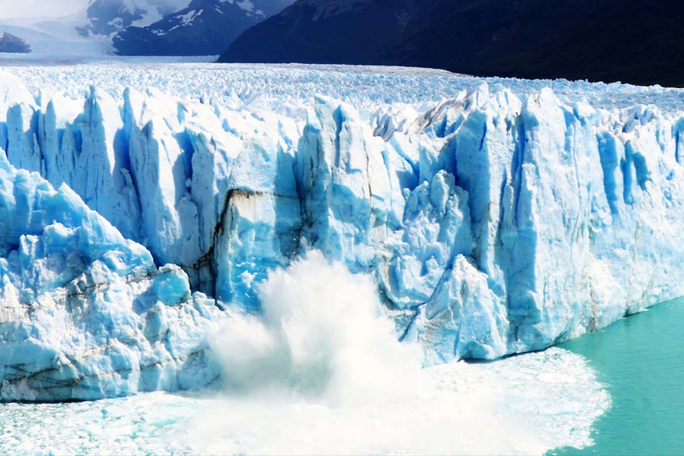 A huge chunk of glacier ice collapsing and falling into the sea