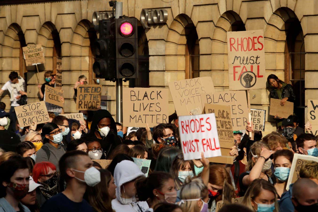2MGE43Y Supporters of the Rhodes Must Fall group, wearing protective masks against the spread of coronavirus, participate in a protest calling for the removal of a statue of Cecil Rhodes, a Victorian imperialist in southern Africa who made a fortune from mines and endowed the university's Rhodes scholarships, beneath the statue which stands on the facade of Oriel College, in Oxford, England, Tuesday, June 9, 2020. More statues of imperialist figures could be removed from Britain's streets, following the toppling of a monument to slave trader Edward Colston in the city of Bristol, the mayor of London s