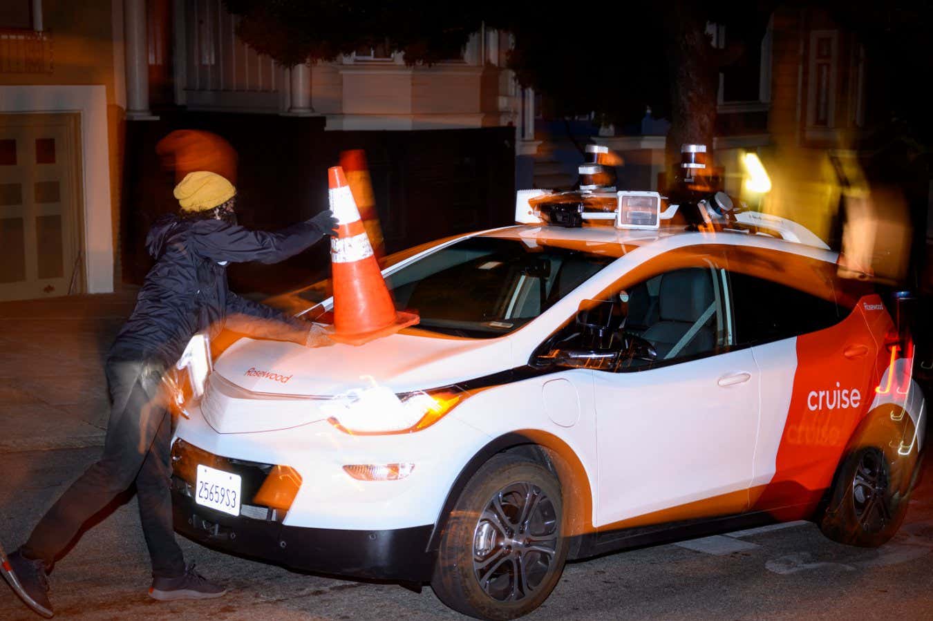 Members of SafeStreetRebel, a group of anonymous anti-car activists, place a cone on a self-driving robotaxi to disable it in San Francisco, California on July 11, 2023. Members of SafeStreetRebel, a group of anonymous anti-car activists, have been actively calling for participants to help protest the spread of robotaxis for malfunctioning and blocking traffic. (Photo by Josh Edelson / AFP) (Photo by JOSH EDELSON/AFP via Getty Images)