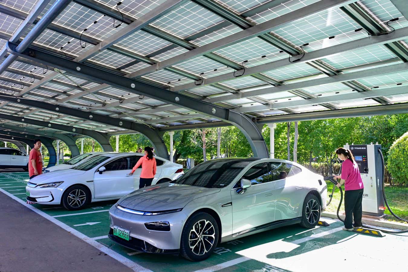 ORDOS, CHINA - JULY 7, 2023 - Citizens use photovoltaic energy from the roof of a shed to charge an electric vehicle at a public parking lot in Ordos, Inner Mongolia, China, July 7, 2023. Ordos City vigorously promotes the construction of photovoltaic power generation projects on the roofs of administrative institutions, government agencies, schools and public parking sheds. (Photo credit should read CFOTO/Future Publishing via Getty Images)