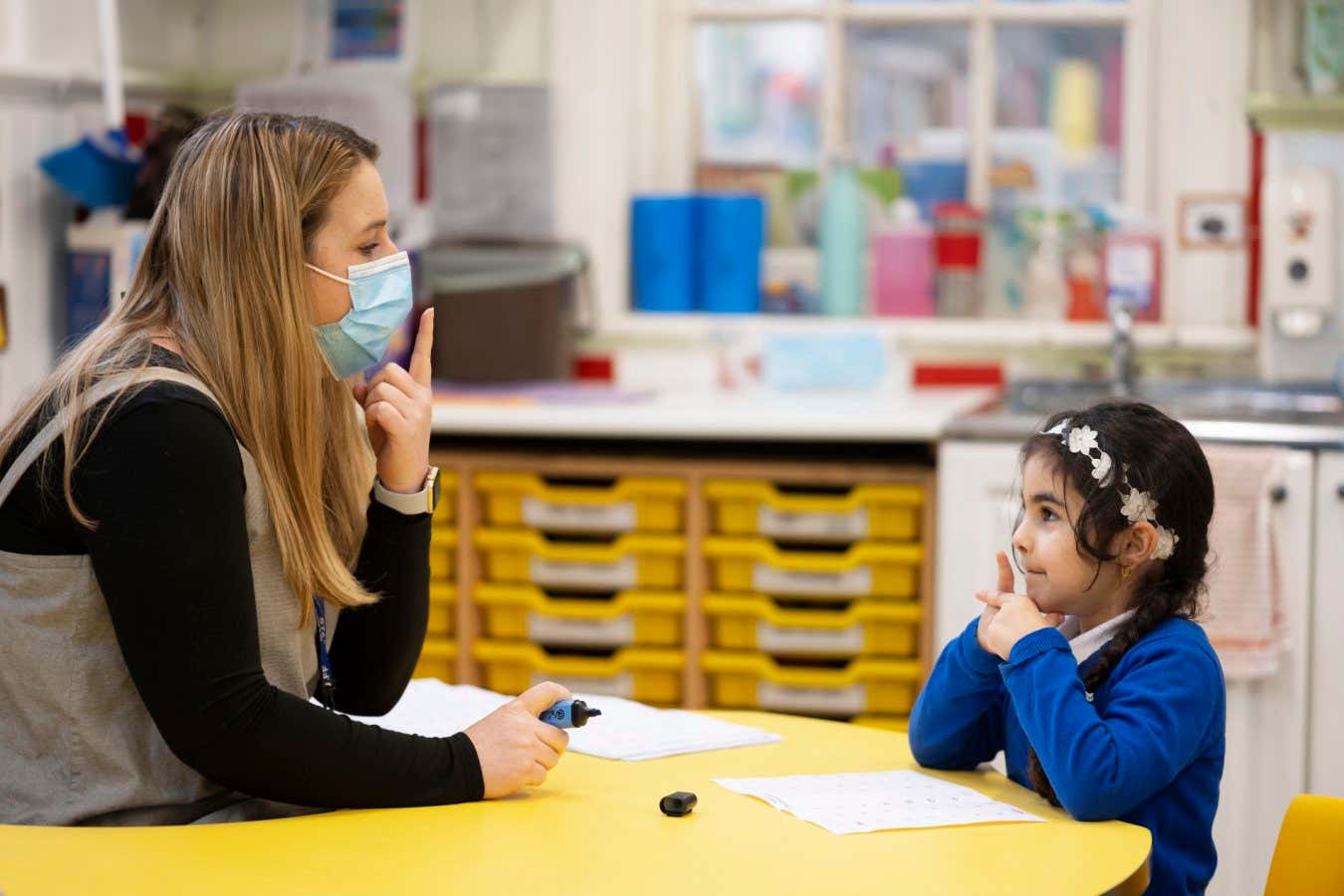 CARDIFF, WALES - FEBRUARY 23: A teacher wearing a face mask teaches a child at Roath Park Primary School on February 23, 2021 in Cardiff, Wales. Children aged three to seven began a phased return to school on Monday. Wales' education minister Kirsty Williams has said more primary school children will be able to return to face-to-face learning from March 15 if coronavirus cases continue to fall. (Photo by Matthew Horwood/Getty Images)