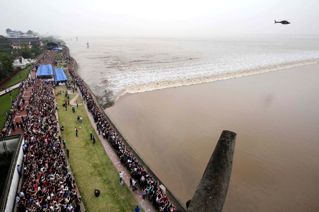 Visitors and local residents throng to watch the tidal bore of the Qiantang River in Haining city