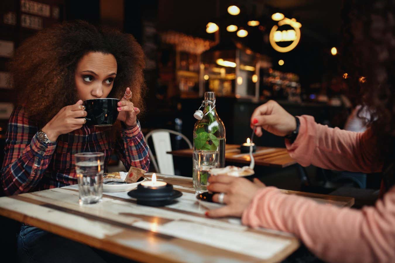 F0A01R Young woman drinking coffee. African girl sitting at cafe having coffee and looking away.