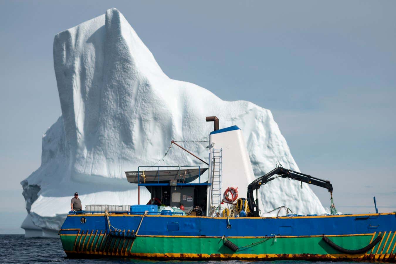 Captain Edward Kean stands on his boat in front of an iceberg in Bonavista Bay on June 29, 2019 in Newfoundland, Canada. - Iceberg water, considered pure, is now marketing for a unique sector of high-end products. 