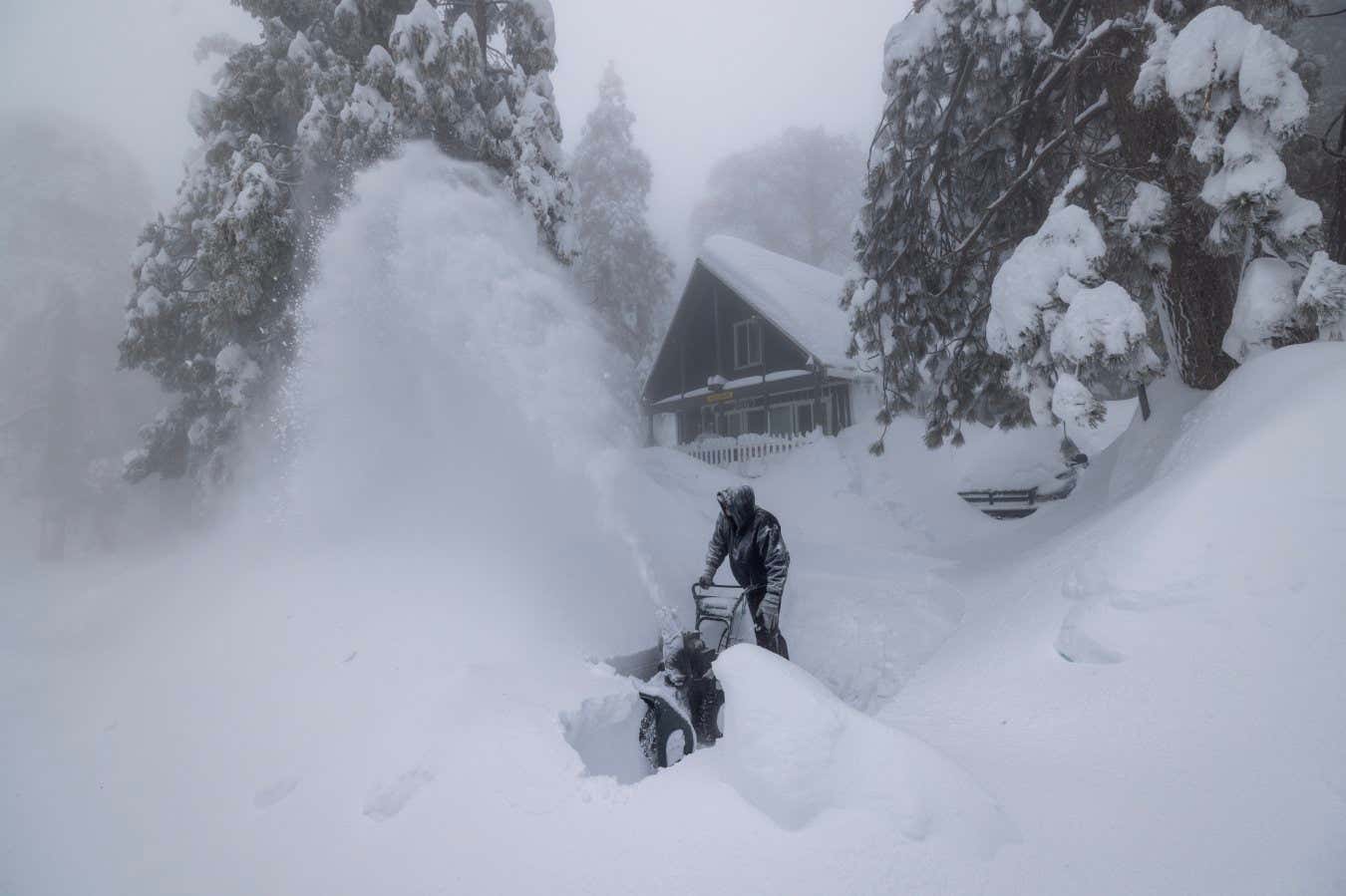 RUNNING SPRINGS, CA - MARCH 01: Robert Hallmark, who says that this is the worst snowstorm of his 31 years living here, clears snow at his home as residents throughout the San Bernardino Mountains continue to be trapped in their homes by snow on March 1, 2023 in Running Springs, California. San Bernardino County has declared a state of emergency as communities remain buried after a series of blizzards shut down all roads into the mountains, leaving the area running low on gas, food and supplies. (Photo by David McNew/Getty Images)