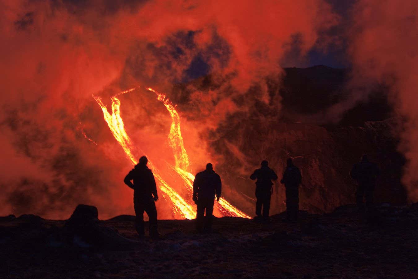 FIMMVORDUHALS, ICELAND - MARCH 24: Hikers are silhouetted against rivers of lava flowing from a volcanic eruption between the Myrdalsjokull and Eyjafjallajokull glaciers on March 24, 2010 in Fimmvorduhals, Iceland. A major eruption occured on April 14, 2010 which has resulted in a plume of volcanic ash being thrown into the atmosphere over parts of Northen Europe. Air traffic has been subject to cancellation or delay as airspace across parts of Northern Europe has been closed. (Photo by Helen Maria Bjornsd/NordicPhotos/Getty Images)