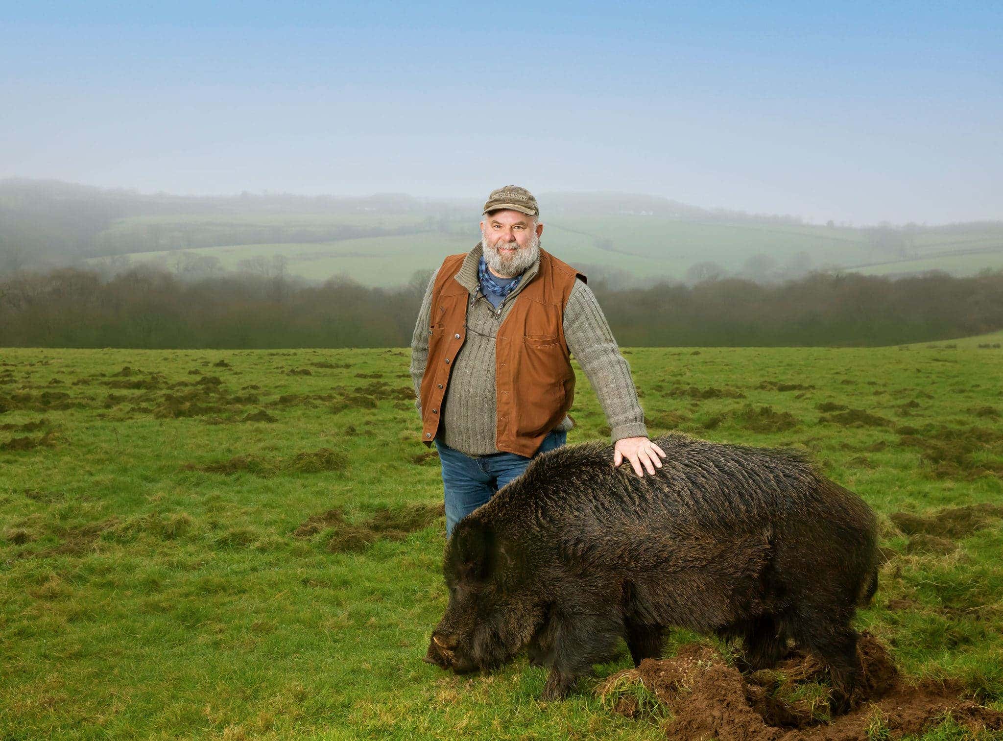 Derek Gow on his rewilding farm in Devon, with bore by his side.