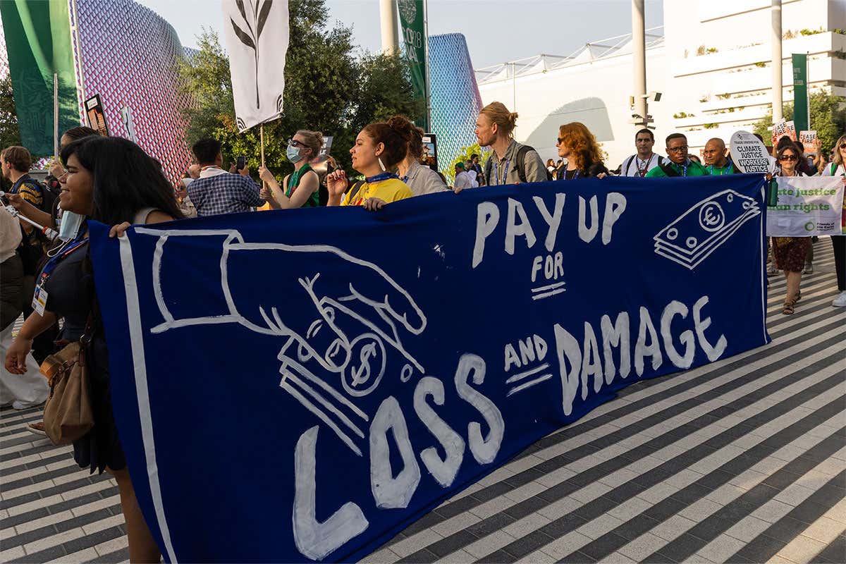 Protestors at COP holding a sign to 'pay up for loss and damage'