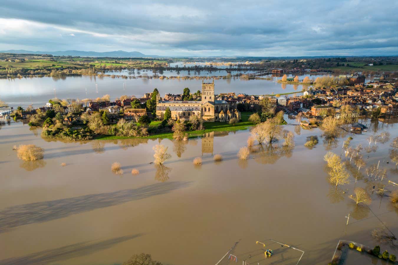 TEWKESBURY, UNITED KINGDOM - JANUARY 05: Flood water surrounds Tewkesbury Abbey and surrounding streets because of widespread flooding after the Rivers Swilgate and Avon burst their banks on January 5, 2024 in Gloucestershire, England. Storm Henk brought strong winds and heavy rain across much of the country this week which lashed large parts of the country, hitting travel and cutting power. While across the UK numerous flood warnings were still in place after weeks of heavy rainfall, the UK's Environment Agency has warned people to expect flooding to become more frequent because of climate change. (Photo by Anna Barclay/Getty Images)