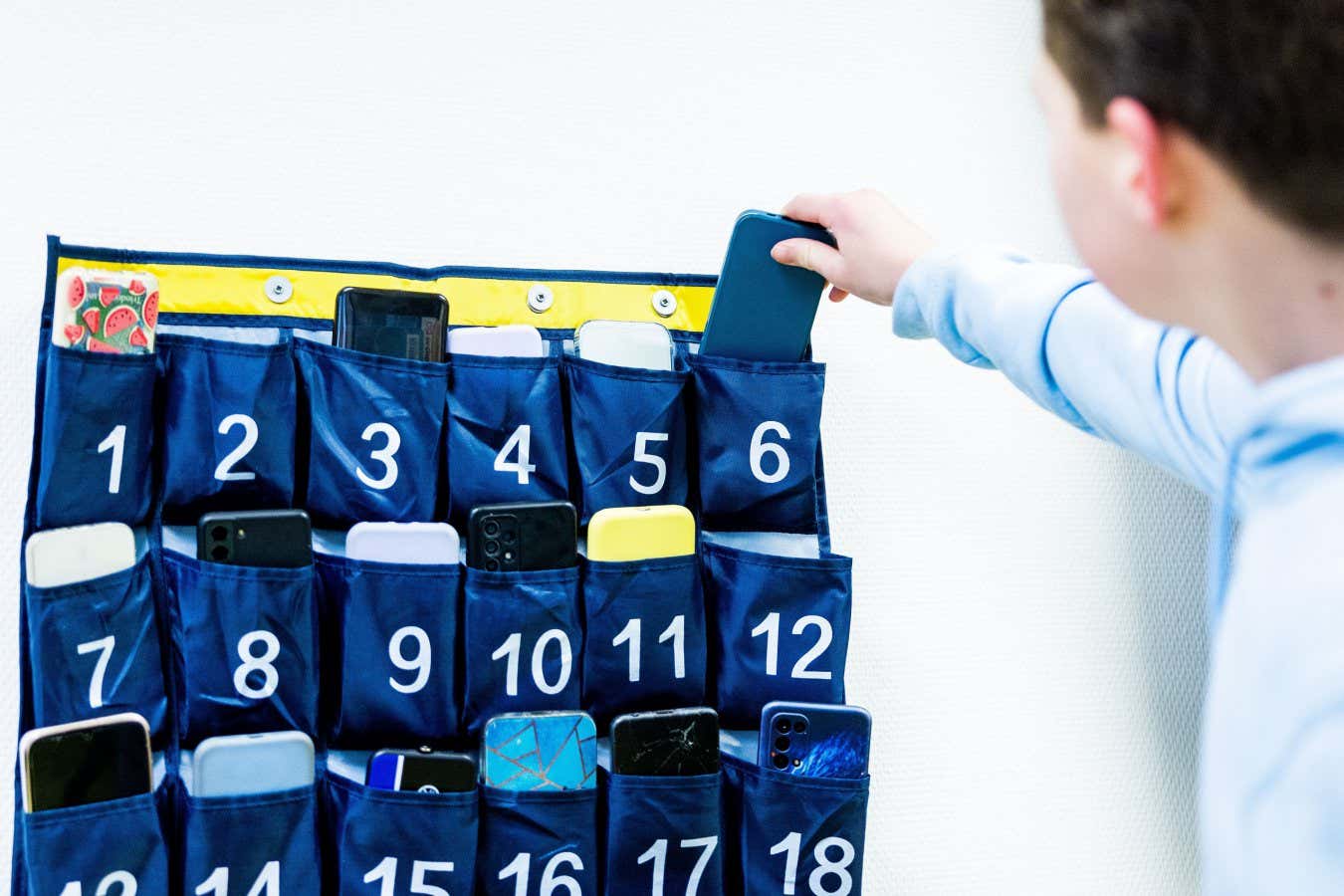 Mandatory Credit: Photo by Hollandse Hoogte/Shutterstock (14291785a) GELDERMALSEN - A student puts his cell phone in a phone pocket at ORS Lek and Linge secondary school. Since January 1, 2024, there has been a national ban on the use of mobile phones in the classroom. High School Phone Ban, Geldermalsen, Netherlands - 09 Jan 2024