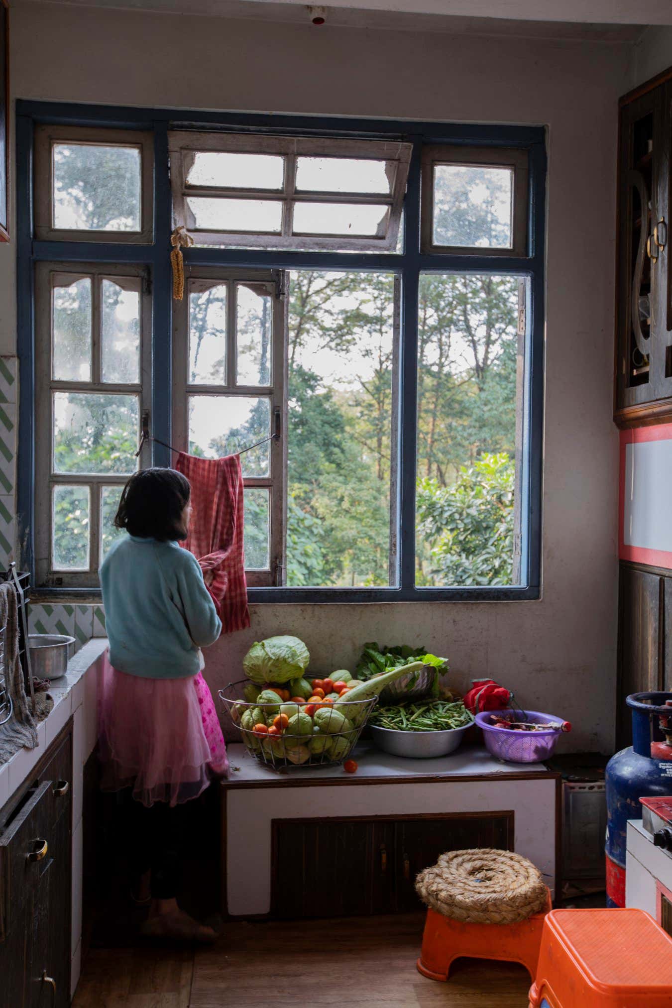 India - Sikkim - A young girl helps her mother in the kitchen of their house, all vegetables are grown in their backyard and are striclty organic.