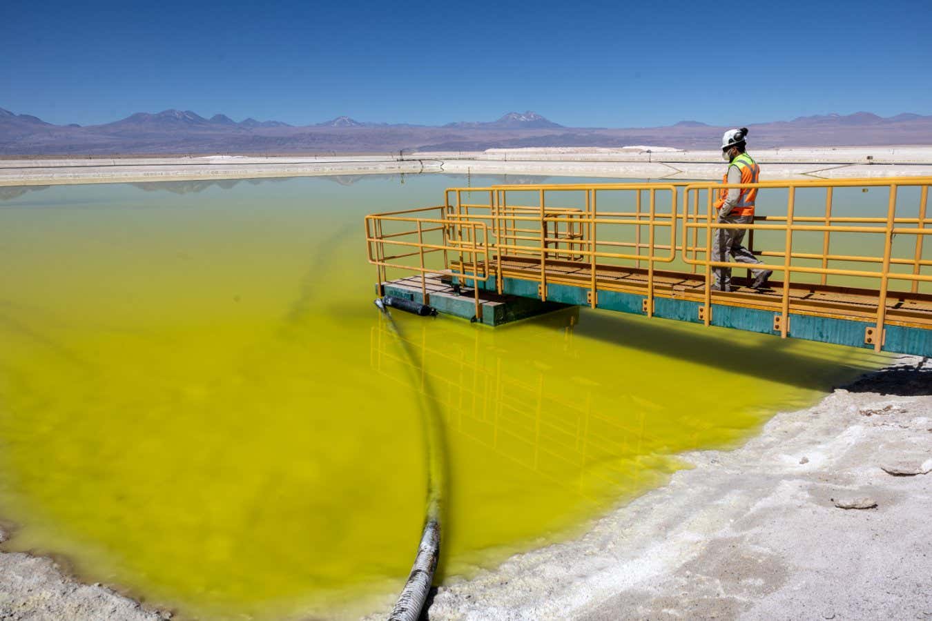SALAR DE ATACAMA, CHILE - AUGUST 24: A lithium mine supervisor inspects an evaporation pond of lithium-rich brine in the Atacama Desert on August 24, 2022 in Salar de Atacama, Chile. Albemarle Corporation, based in Charlotte, N.C. is expanding mining operations at their Salar Plant to meet the rising global demand for lithium carbonate, a main component in the manufacture of batteries, increasingly for electric vehicles. To extract the lithium, natural brine is pumped from under the salt flats to a series of evaporation ponds. During an 18-month process, the liquid s moved through 15 ponds, eventually turning from blue to yellow with a lithium concentration of 6 percent. It is then trucked to an Albemarle chemical plant in Antofagasta, where it is processed into battery grade lithium carbonate powder and shipped out internationally. The evaporation process produces large quantities of salt byproduct, much of which is then reprocessed and sold. Chile is the second largest global producer of lithium, after Australia. (Photo by John Moore/Getty Images)