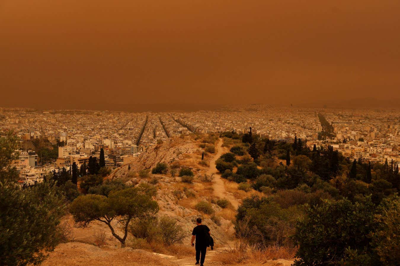 A man makes his way at a hill as African dust from the desert of Sahara covers the city of Athens, Greece, April 23, 2024. REUTERS/Louisa Gouliamaki TPX IMAGES OF THE DAY - RC2FC7ATEP85